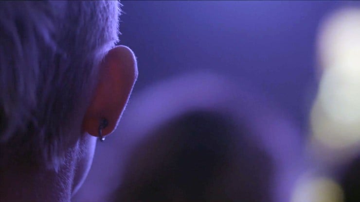 Close up on the back of a person's ear in a blue room.